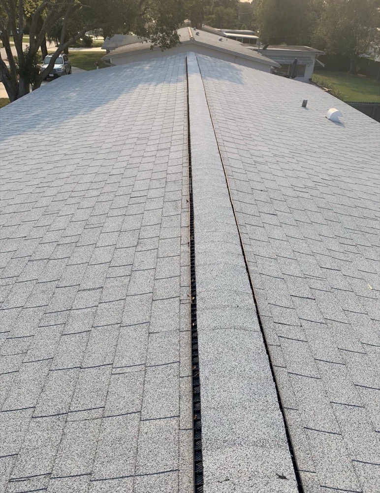 Continuous ridge vent running along the peak of a shingle roof, providing exhaust ventilation for the attic below
