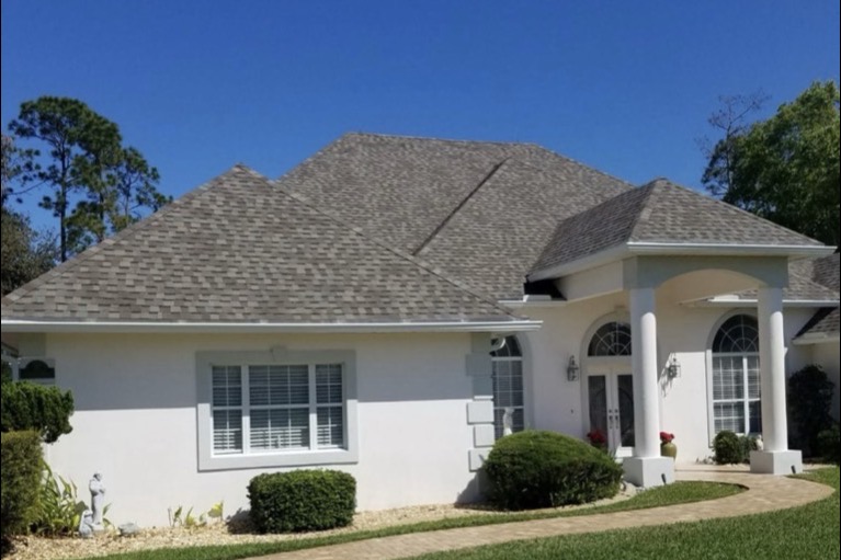 Florida stucco home with an aging but intact grey shingle roof, the kind insurers are targeting for non-renewal based on age alone