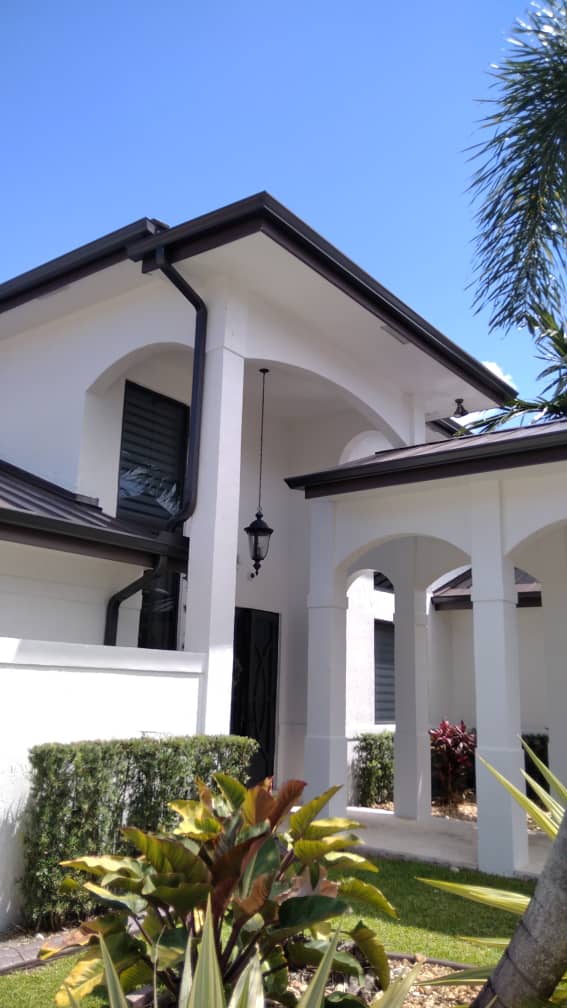 Two-story white stucco Florida home with dark seamless gutters and downspouts matching the roofline trim