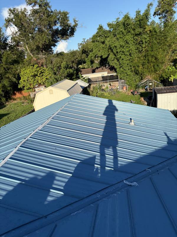 Blue standing-seam metal roof panels and ridge cap on a home