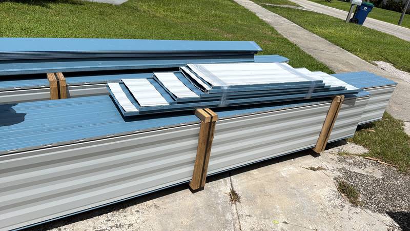 Bundles of blue and white metal roofing panels delivered to a job site