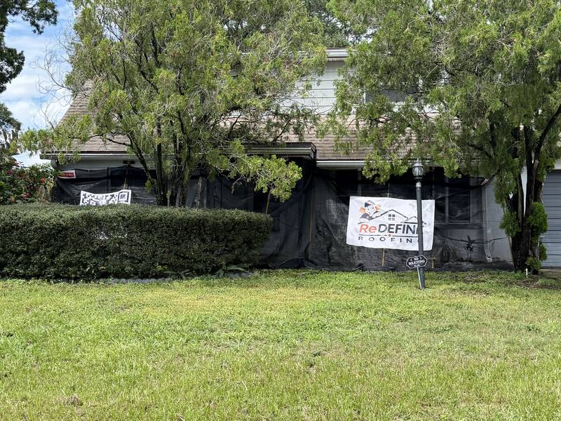 Redefine Roofing logo banner displayed in front of a home during a roofing project