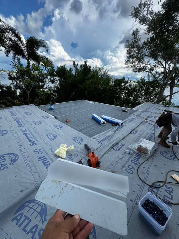 Roof deck covered with synthetic underlayment, with tools and materials on the roof